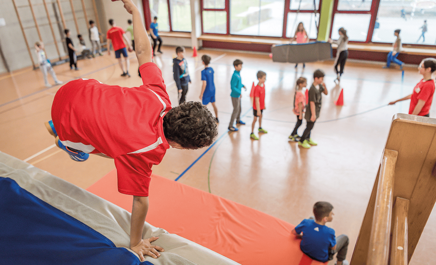 Image of children participating in physical activities in a gymnasium as part of IdéeSport's OpenSunday program.